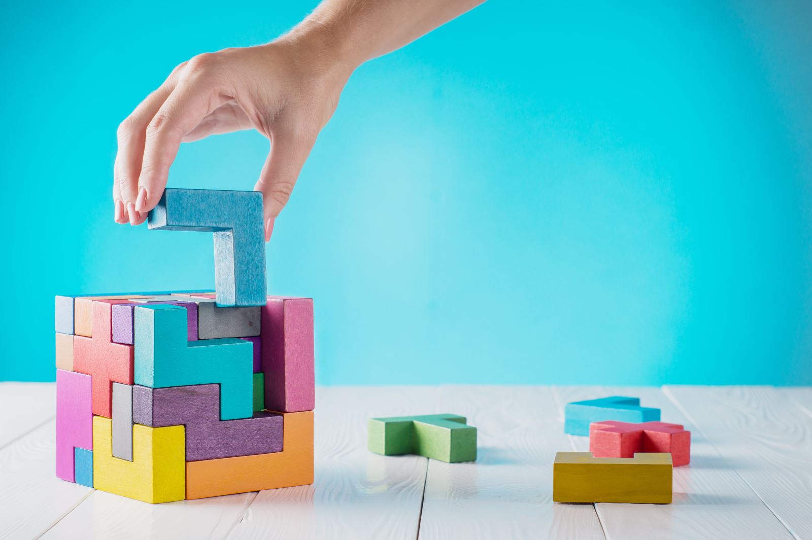 Image of an arm placing a 3D jigsaw piece into place to create a cube.