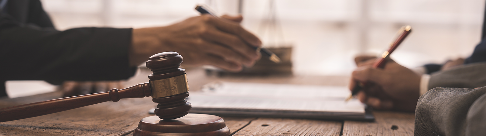 A view of two people working at a desk, with justice scales in the background