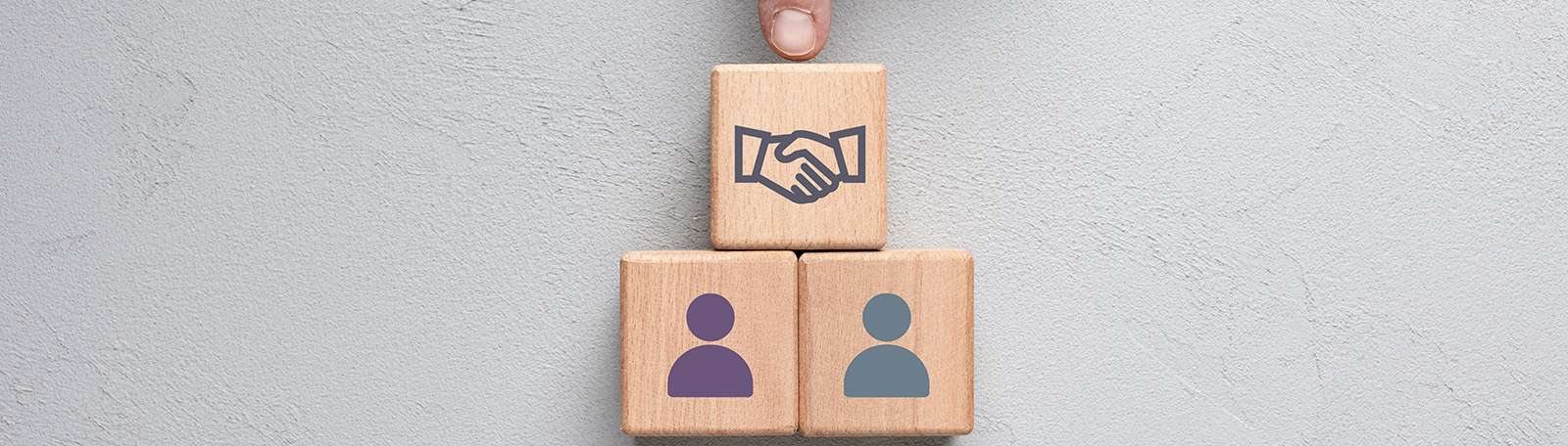 A graphic of two people icons on wooden blocks, with a mediator icon of shaking hands above