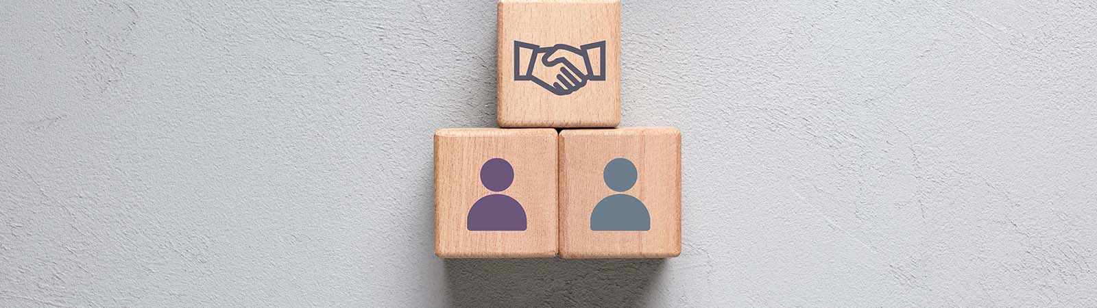 A graphic of two people icons on wooden blocks, with a mediator icon of shaking hands above
